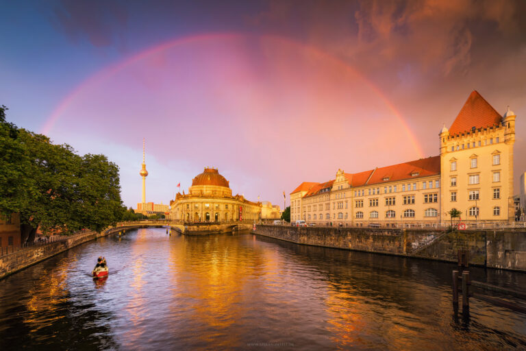 Sonnenuntergang mit Regenbogen in Berlin über der Museumsinsel mit Fernsehturm im HG in malerisch-bunter Stimmung. Aufziehendes Unwetter mit düsteren Wolken