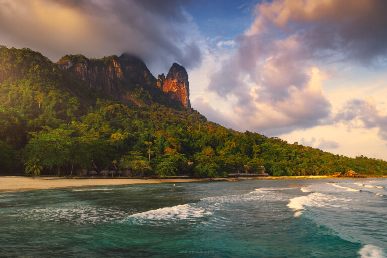 Pulau Tioman, Malaysia im warmen Licht des Sonnenuntergangs. Der markante Berg Dragon Horn rot strahlend vor üppigem Dschungel und rauer See