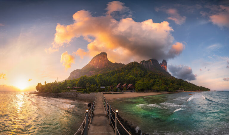 Paradiesisches Inselpanorama von Pulau Tioman mit den ikonischen Felsbergen und üppiger tropischer Vegetation in stimmungsvollem warmen Sonnenuntergangslicht